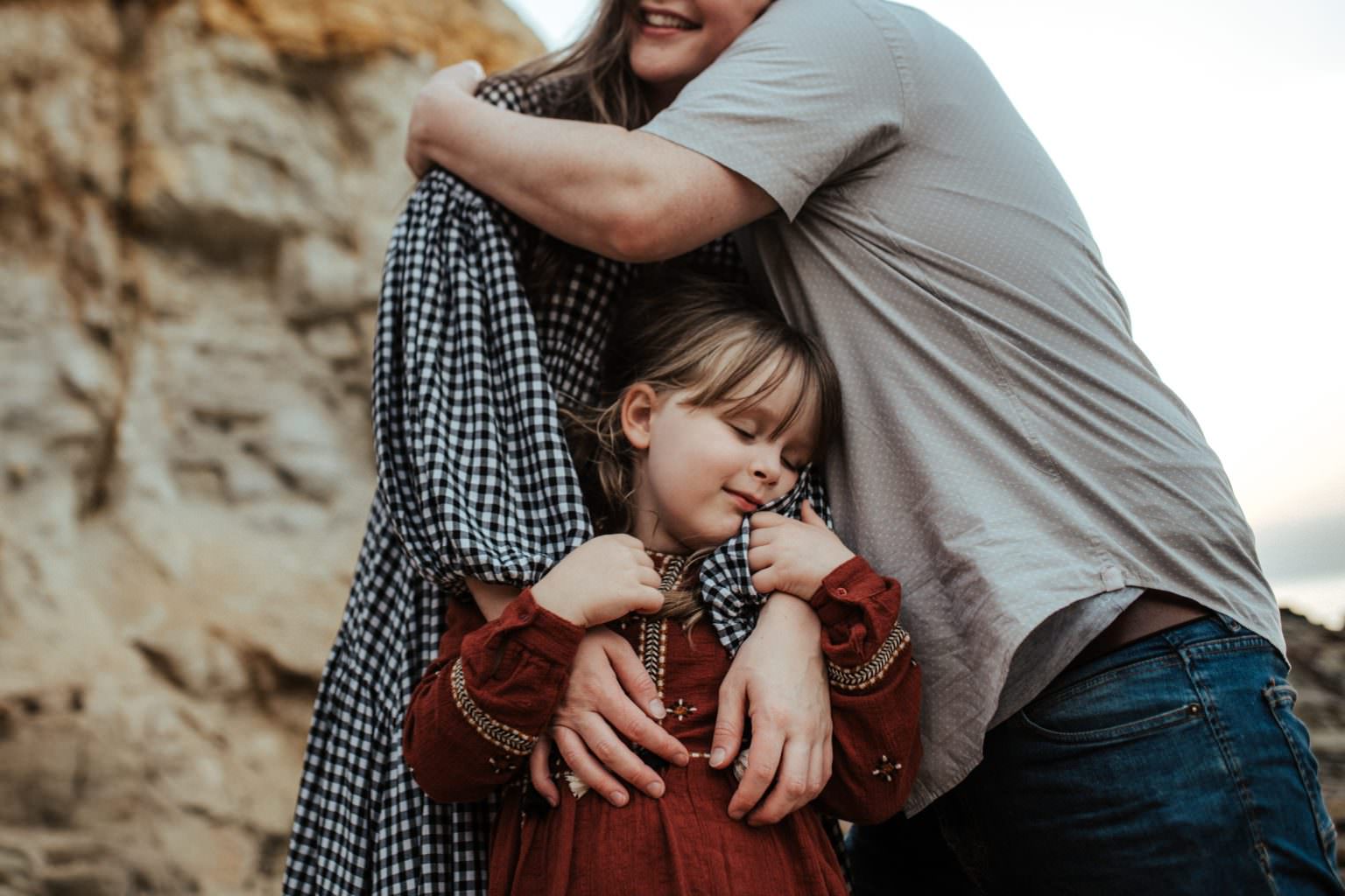 Melbourne family photographer Bec Matheson photographs a Little girl holding her mothers hands, the parents embracing in the back