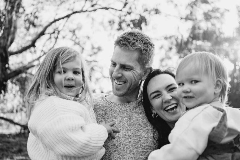 Photo of a Melbourne family laughing naturally together in the bushland the image is black and white