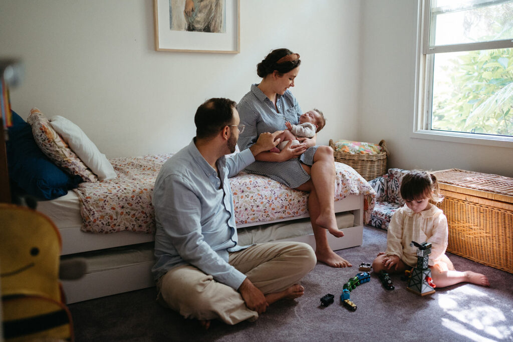 a family sit in a bedroom the toddler plays with blocks