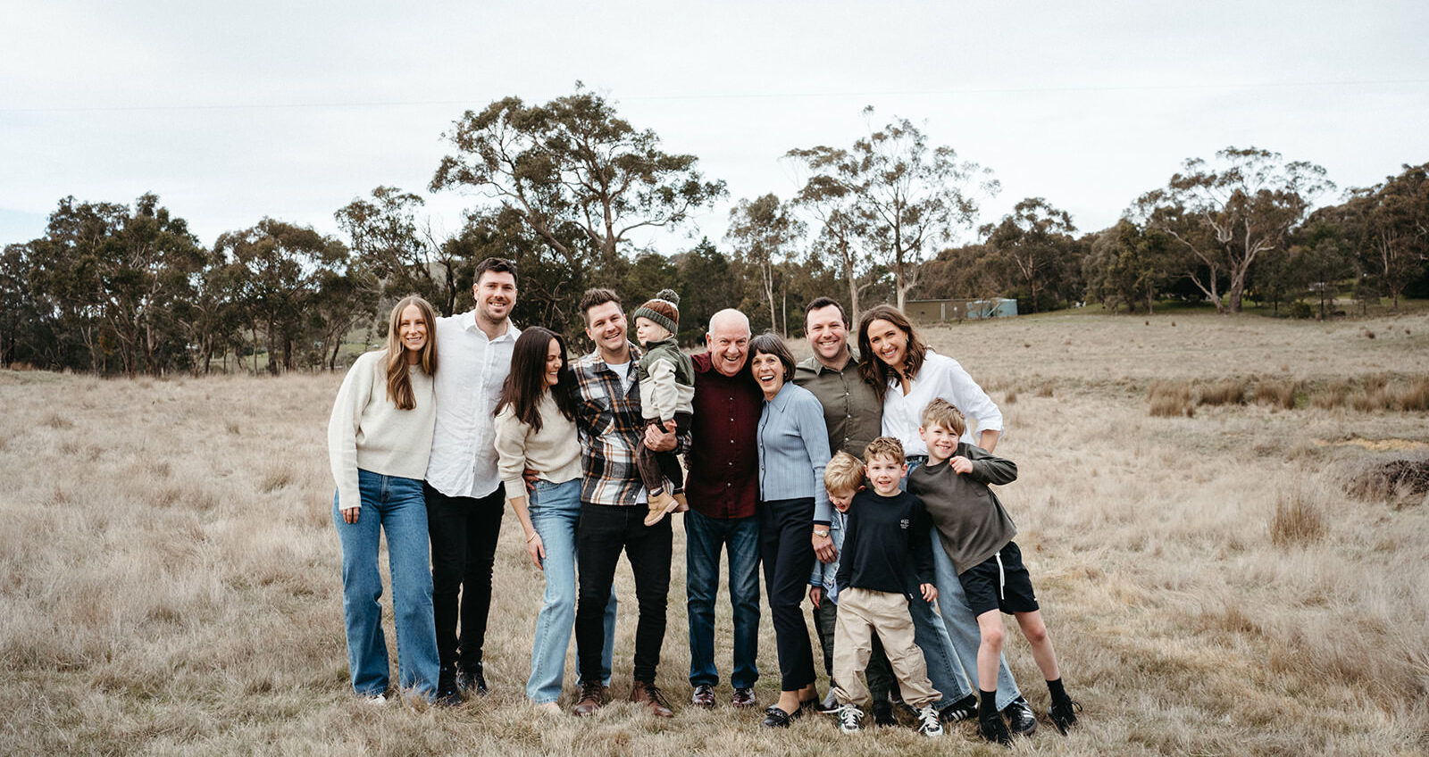 a large family photo of a group wearing coordinated clothing on a farm standing together smiling