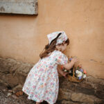a girl in a floral dress picks flowers kids clothing brand