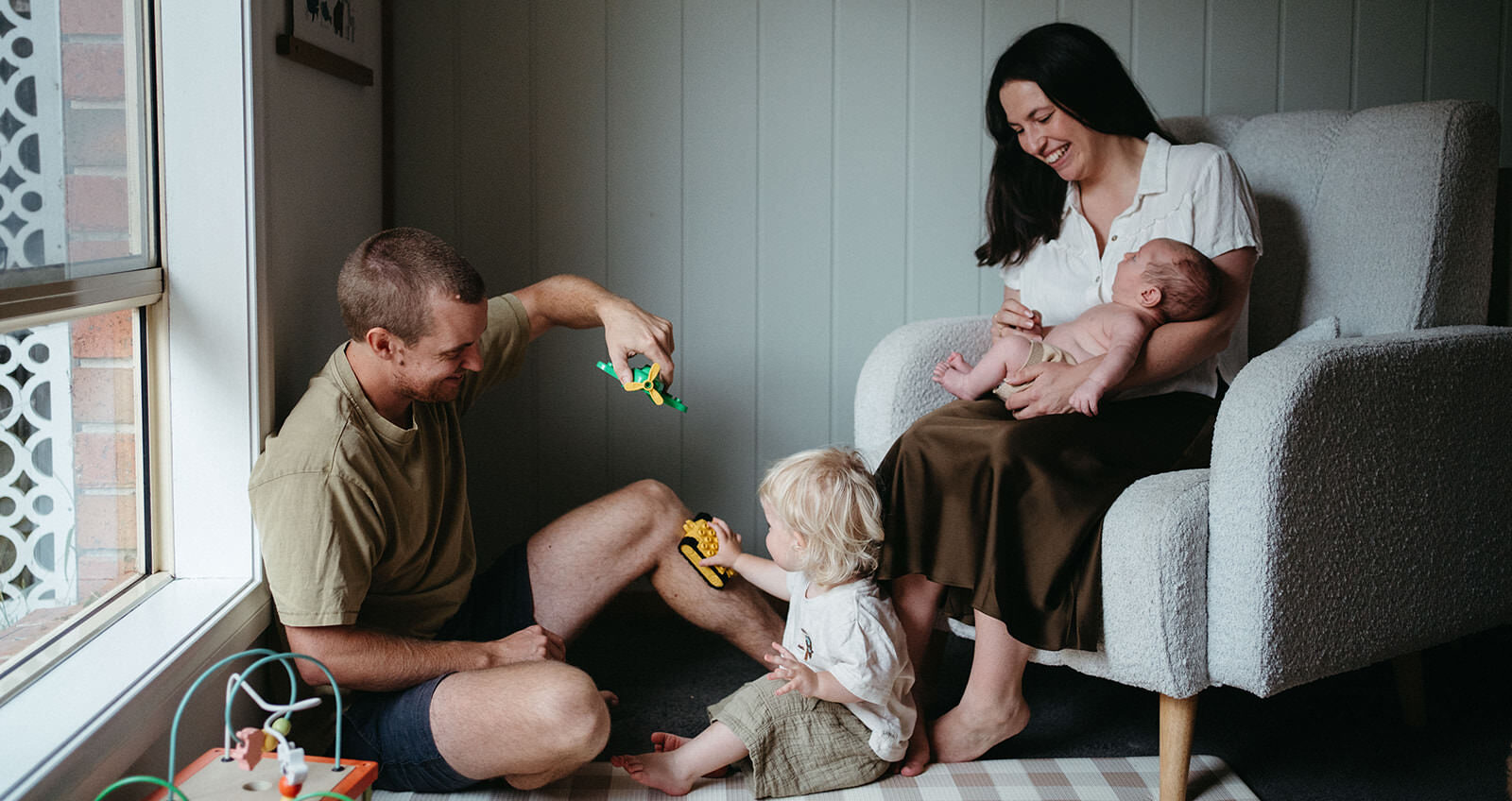 Playful in-home newborn session in Melbourne with dad flying toy airplane for toddler during natural family photography