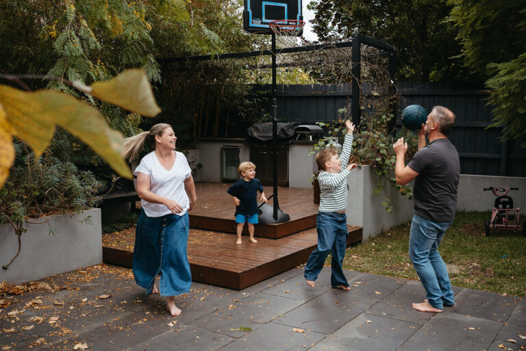 a family of four and parents are teaching their kids how to play basketball in their backyard in Melbourne