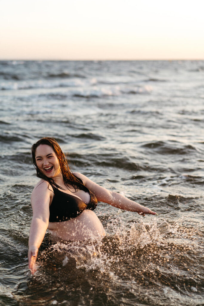 a pregnant woman swims in the ocean she is laughing 